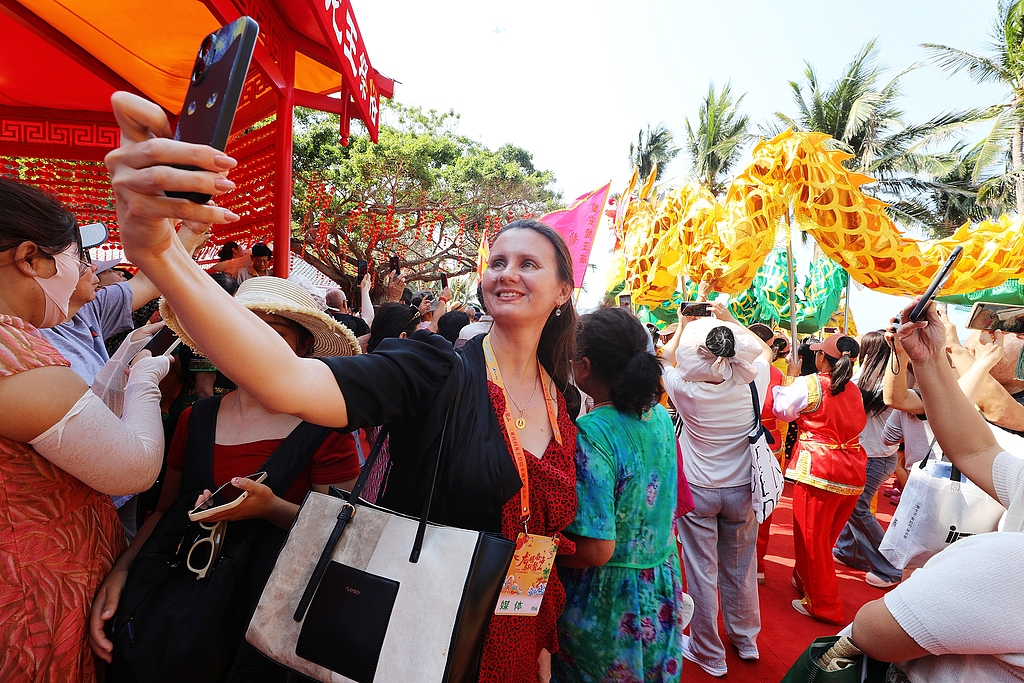 A foreign tourist takes a selfie in Sanya, Hainan Province, on March 20, 2026. /VCG