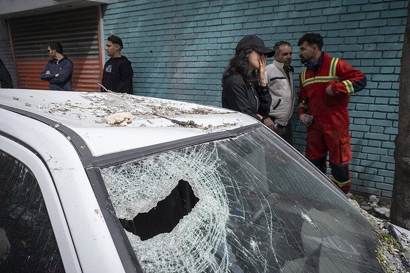 A rescue team member and residents stand behind a vehicle destroyed in an airstrike on a residential building in Tehran, Iran, March 27, 2026. /Xinhua