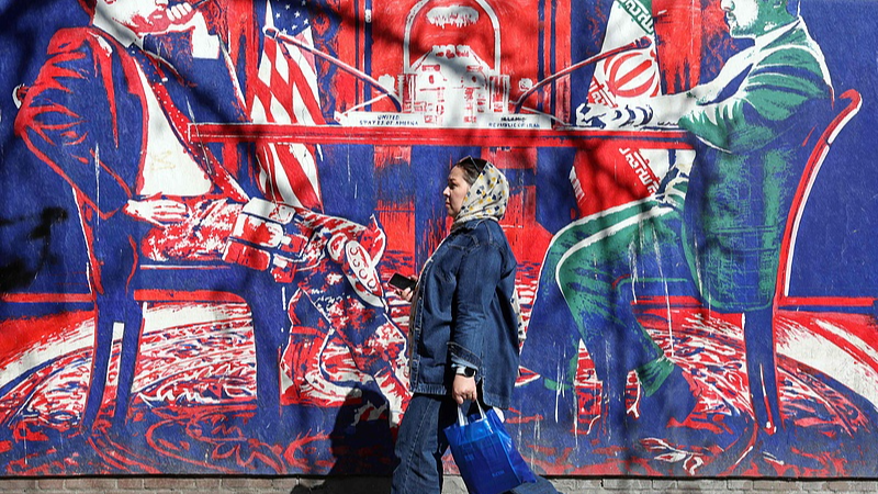 An Iranian woman walks past an anti-US mural featuring Iran-US talks, next to the former US Embassy in Tehran, Iran, February 26, 2026. /VCG