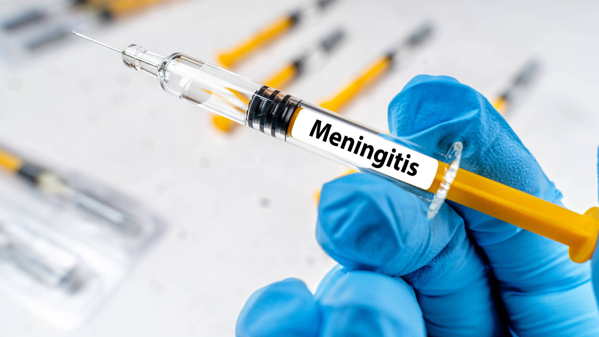 A doctor holds a syringe labeled 