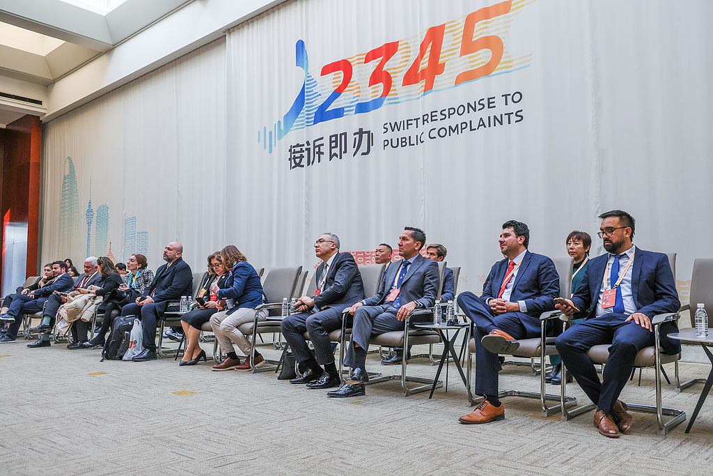 International guests visit the Beijing 12345 Citizen Hotline Service Center to learn about the city's Swift Response to Public Complaints mechanism, in Beijing, China, December 17, 2024. /VCG