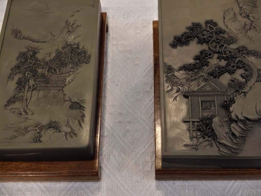 Two inkstones with landscape themes are displayed side by side at the 56th National Four Treasures of the Study Art Expo in Beijing on March 27, 2026. Carved in fine detail, the tiny pavilions and towers seem to come alive, while ancient pine trees stand like wise sages. /VCG