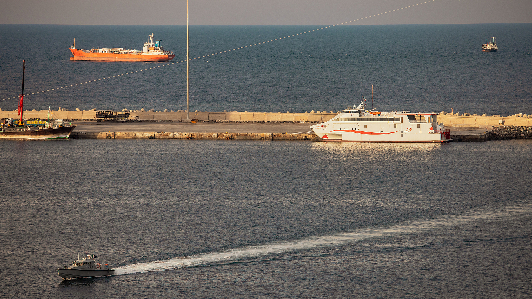 A police speedboat patrols the port as oil tankers and high-speed vessels sit anchored at Muscat Anchorage near the Strait of Hormuz on March 30, 2026, Muscat, Oman. /CFP
