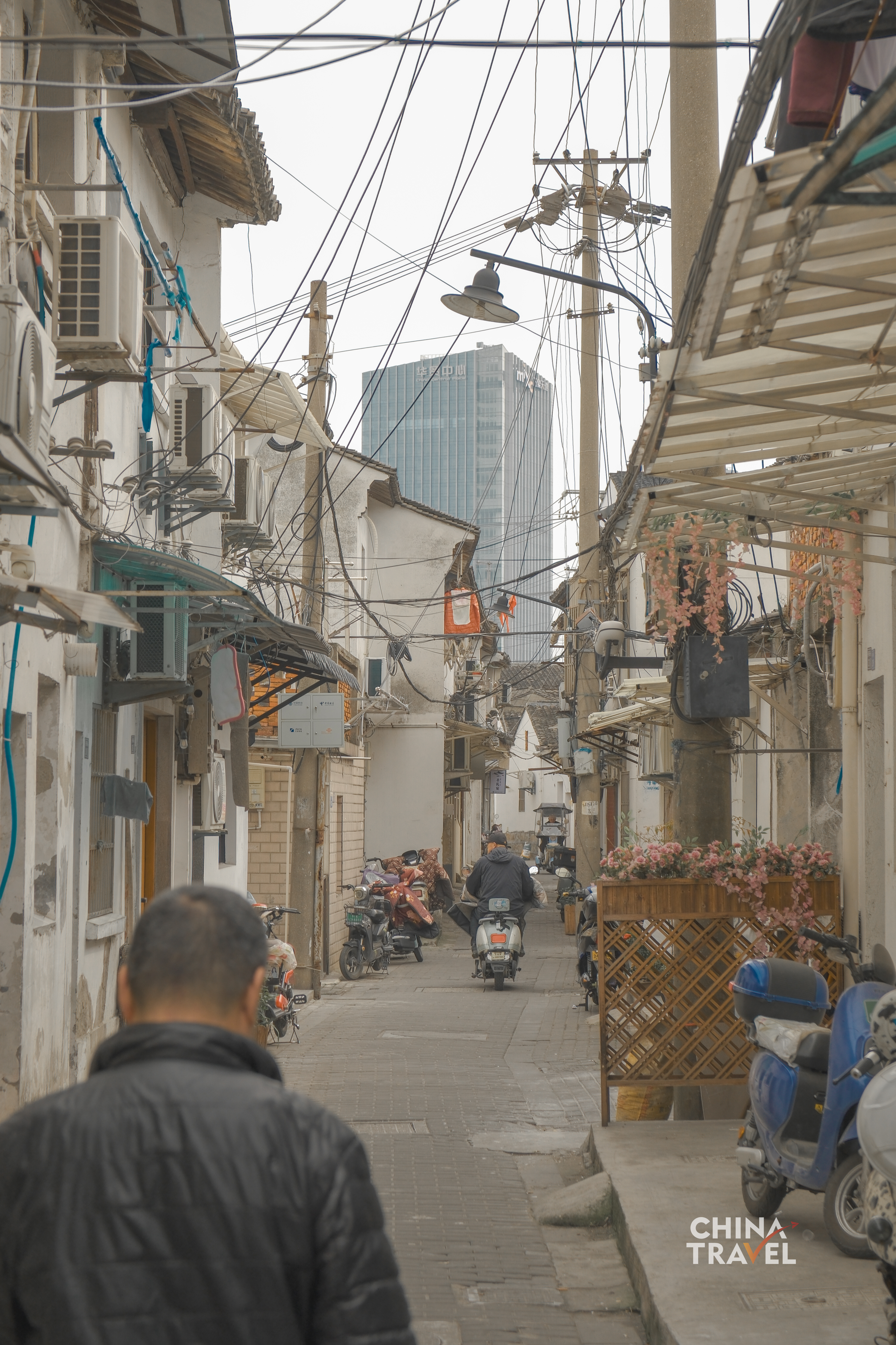 In Suzhou's narrow lanes, tangled wires, food stalls and passing residents sketch out the texture of everyday urban life. /CGTN