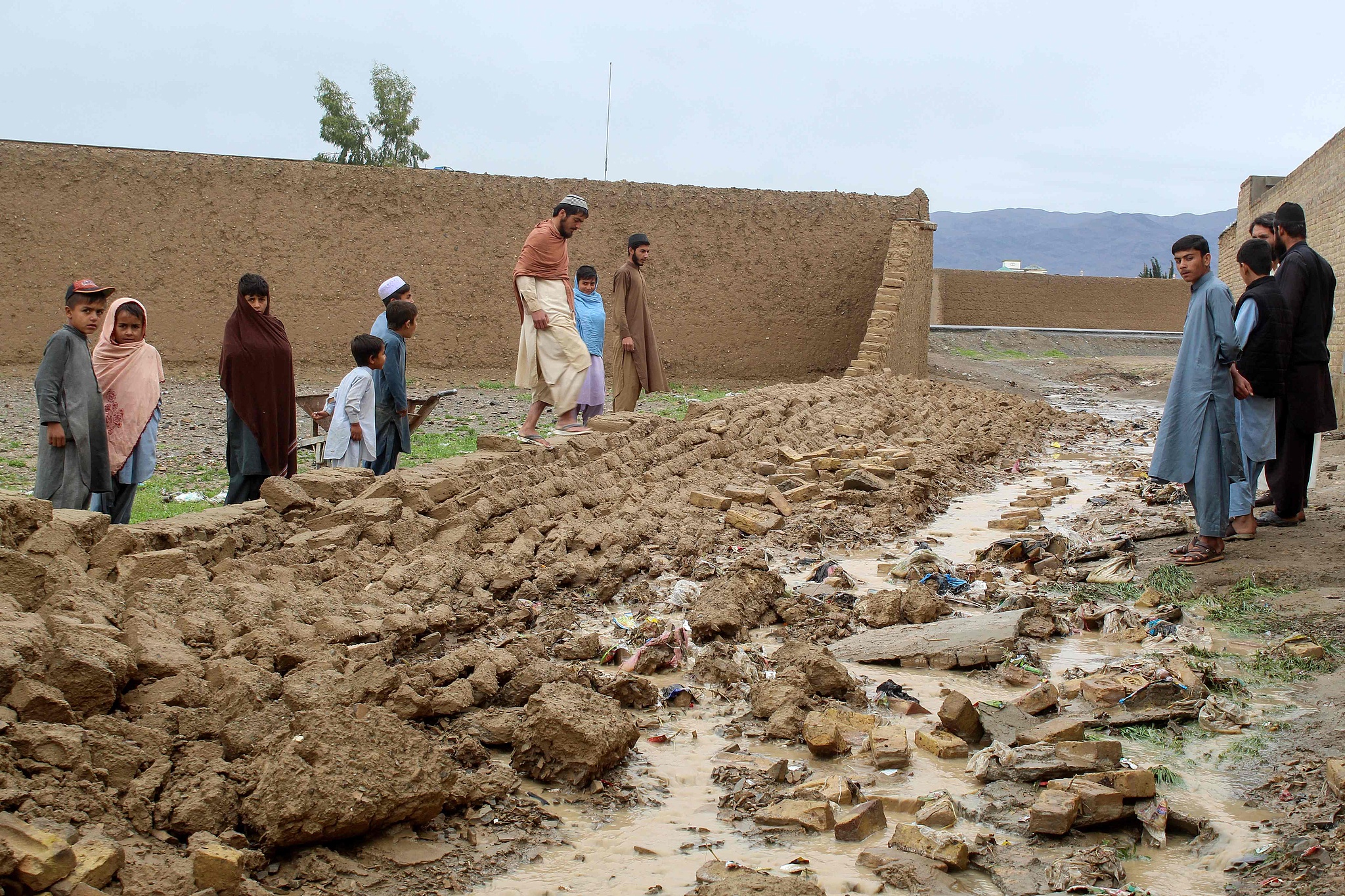 Residents gather beside the collapsed mud wall of a house during heavy rains in Chaman, Pakistan, April 2, 2026. /VCG