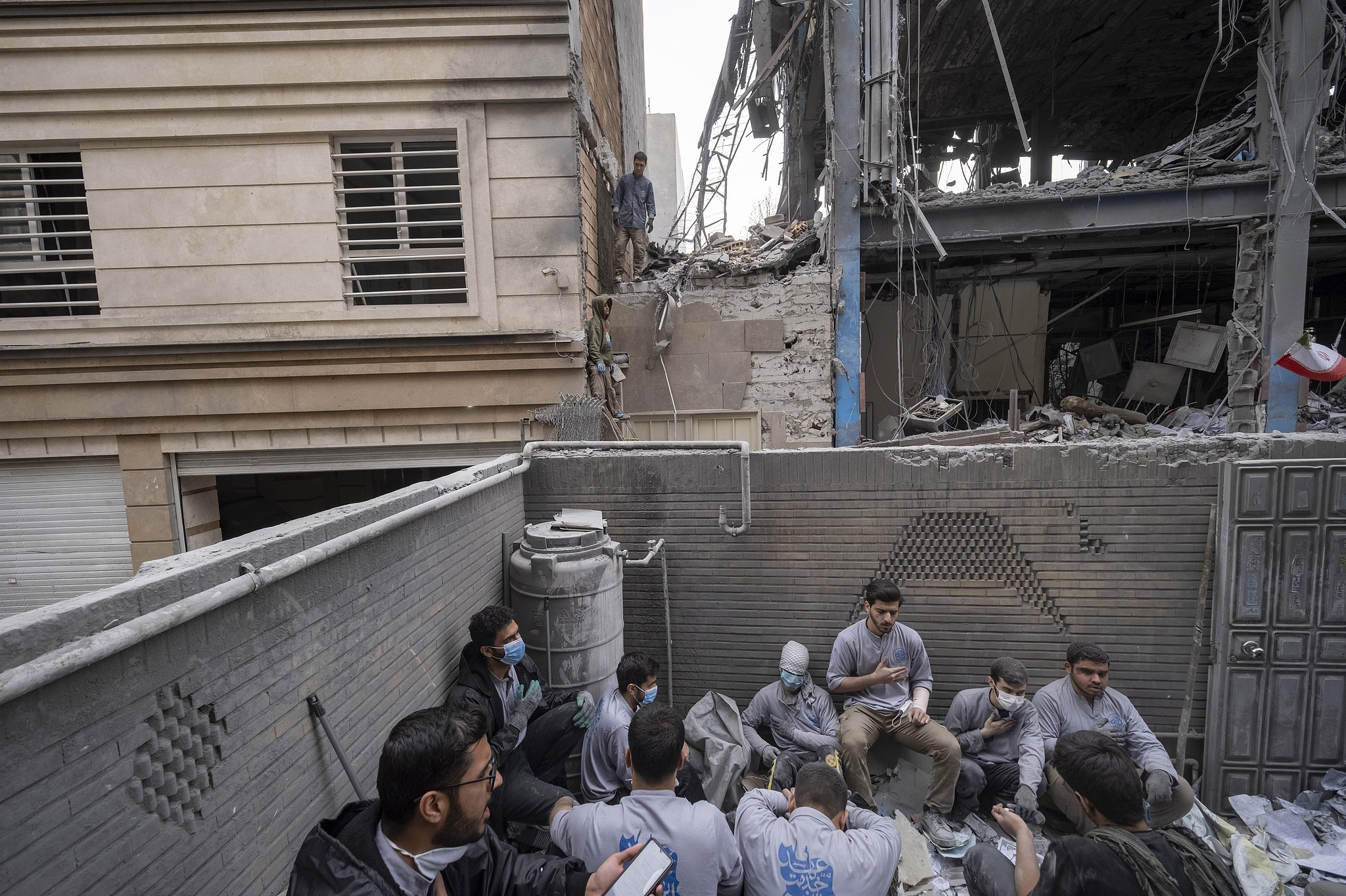 A group of Iranian volunteers mourn while sitting on the ruins of a building near a police station in a residential area in Tehran, Iran, on March 15, 2026. /VCG