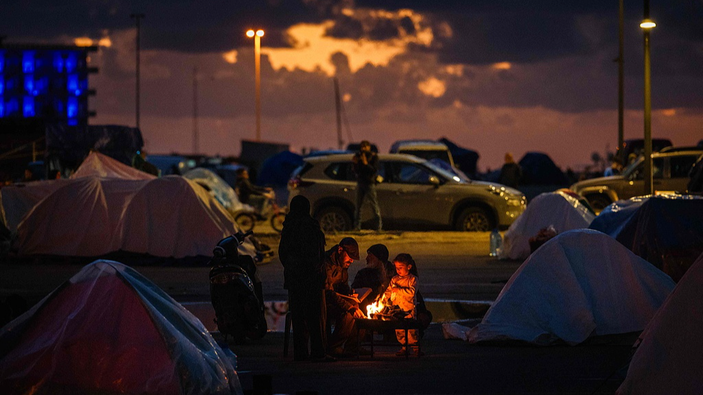 Displaced people warm up around a fire outside their tent along Beirut's seafront area in Lebanon, March 30, 2026. /VCG