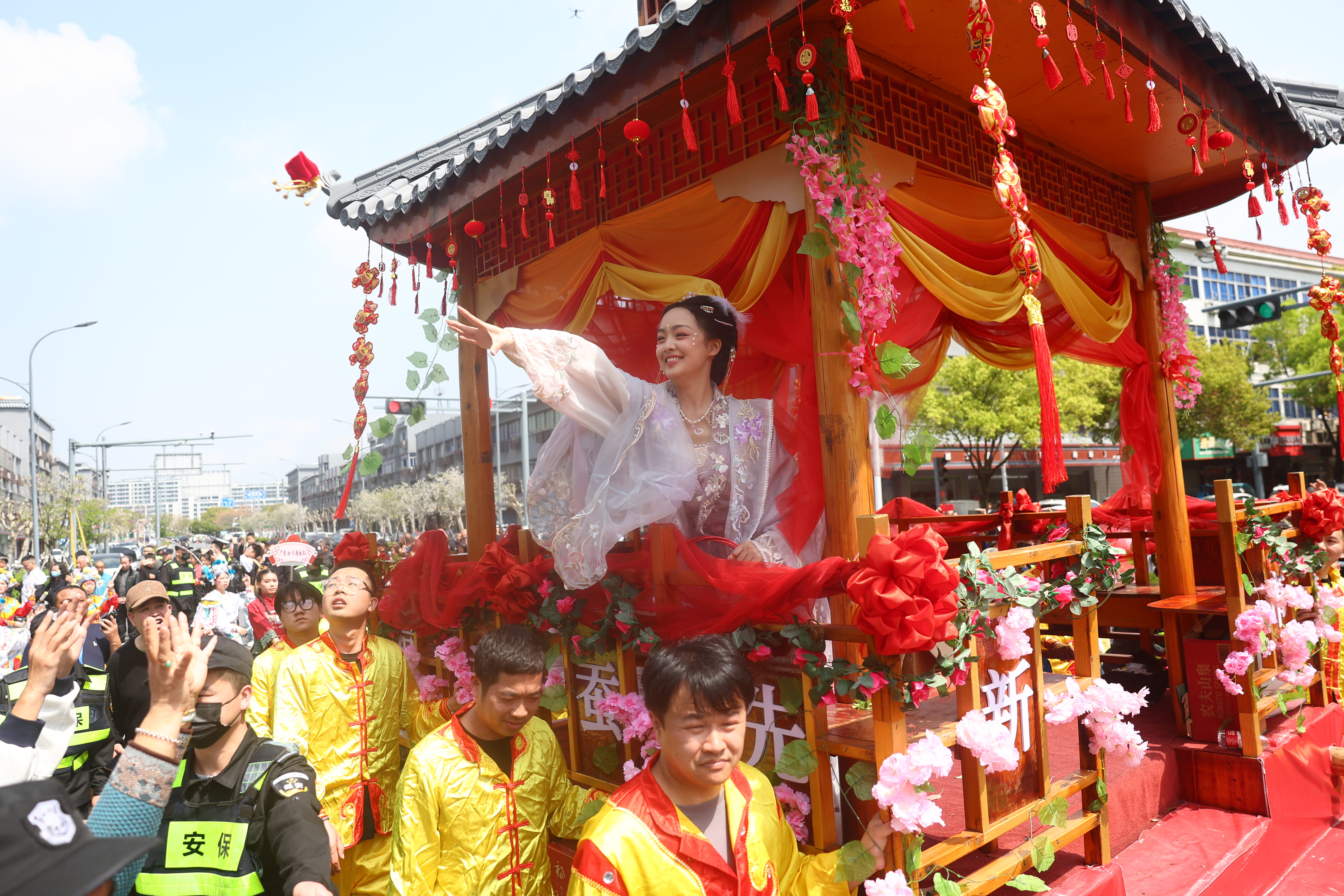 A silkworm flower maiden tosses silkworm flowers to the crowds, spreading blessings for a rich silkworm harvest as the procession moves through Xinshi Ancient Town in Deqing County, Zhejiang Province on April 4, 2026. /CGTN