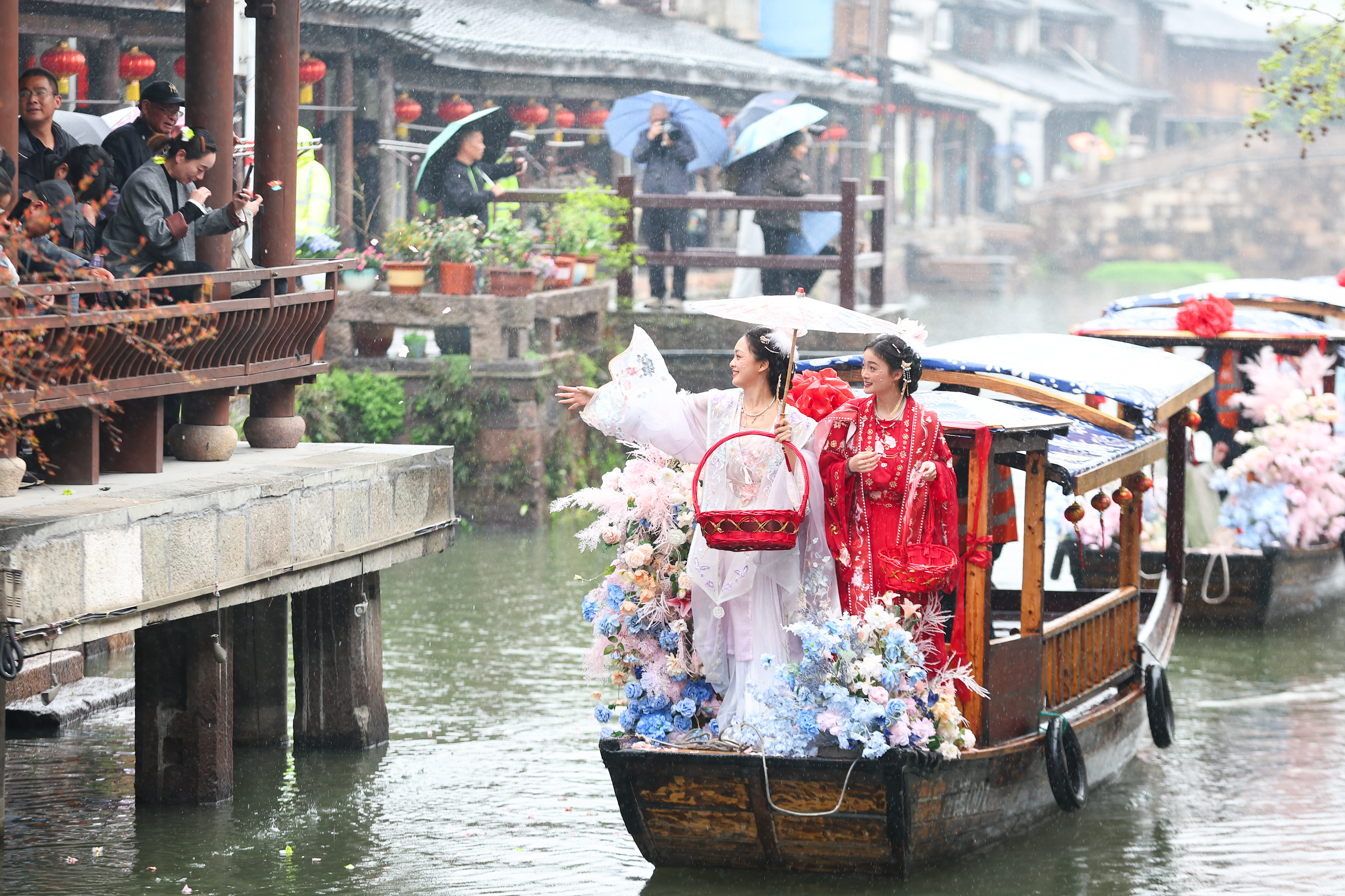 Reviving an ancient custom, silkworm flower maidens scatter flowers on the water along the canals of the millennium-old Xinshi water town in Deqing County, Zhejiang Province on April 4, 2026. /CGTN