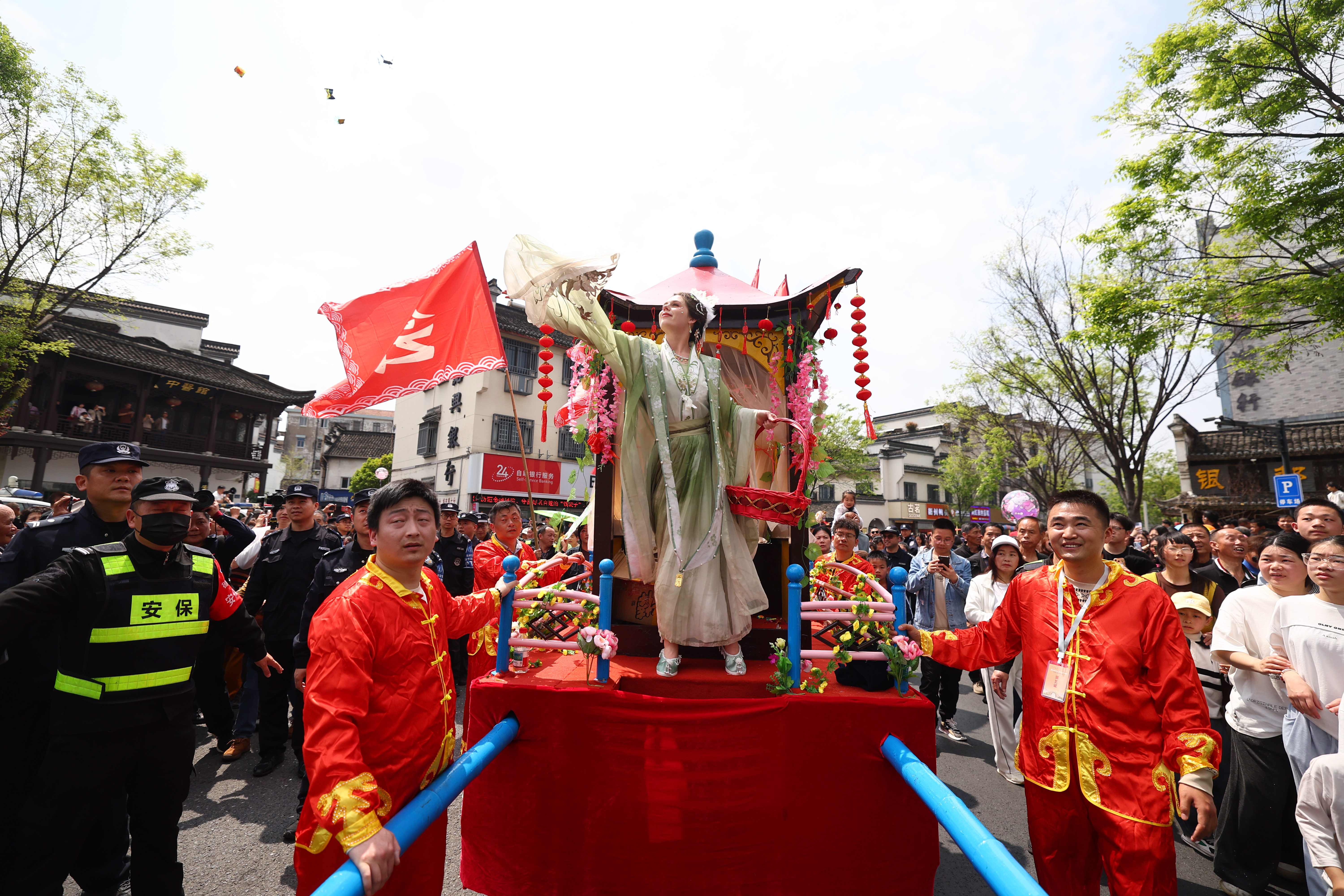 A visitor from Belarus named Anna steps aboard a palanquin at the Silkworm Flower Festival in Xinshi Ancient Town in Deqing County, Zhejiang Province on April 4, 2026. /CGTN 