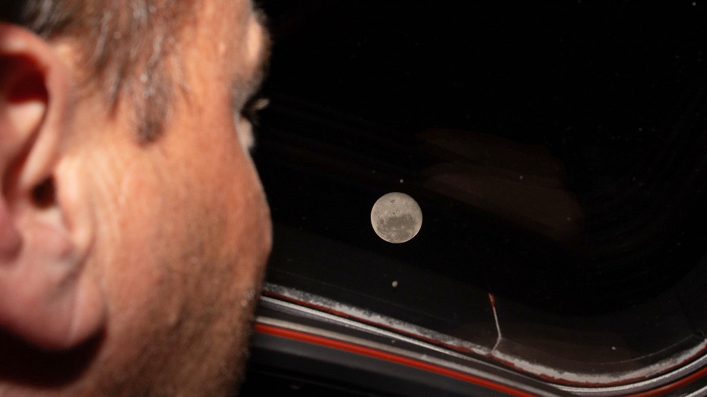 Artemis II commander and NASA astronaut Reid Wiseman looks out one of the Orion spacecraft's main cabin windows at the moon ahead of the crew's lunar flyby, April 6, 2026. /VCG