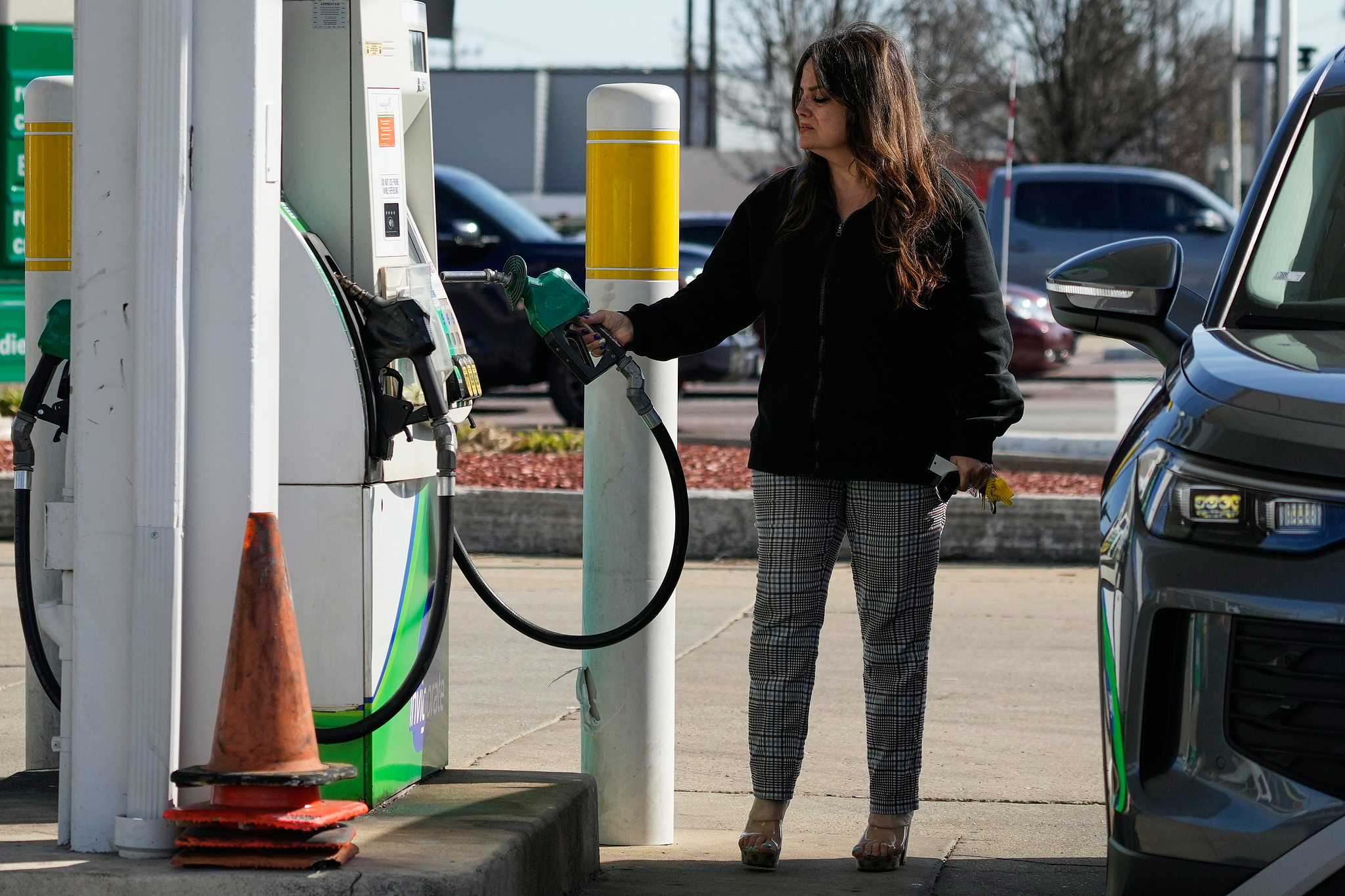 A woman checks gas prices before she fills up her vehicle's tank at a gas station, in Morton Grove, Illinois, April 7, 2026. /CFP