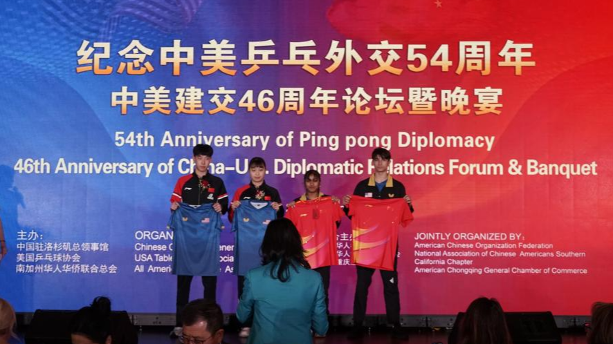 Table tennis athletes from China and the United States exchange uniforms during a reception to commemorate the 54th anniversary of China-US 