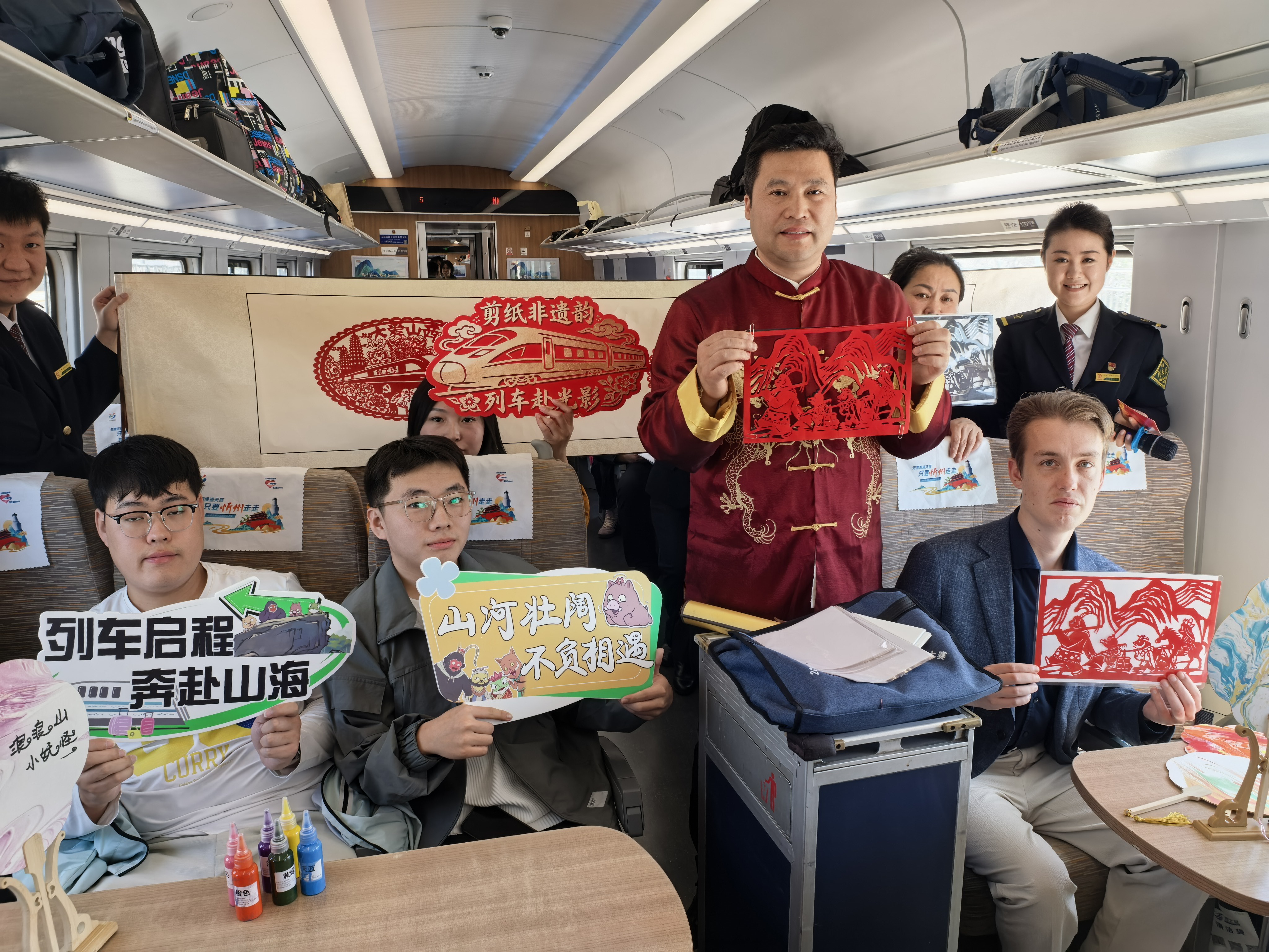 Along with other travellers, British traveler Rees Tyrrell displays a paper cutting on a movie-themed high-speed train inspired by the Chinese 2D animated film Nobody, in this photo taken on April 10, 2026. /CGTN