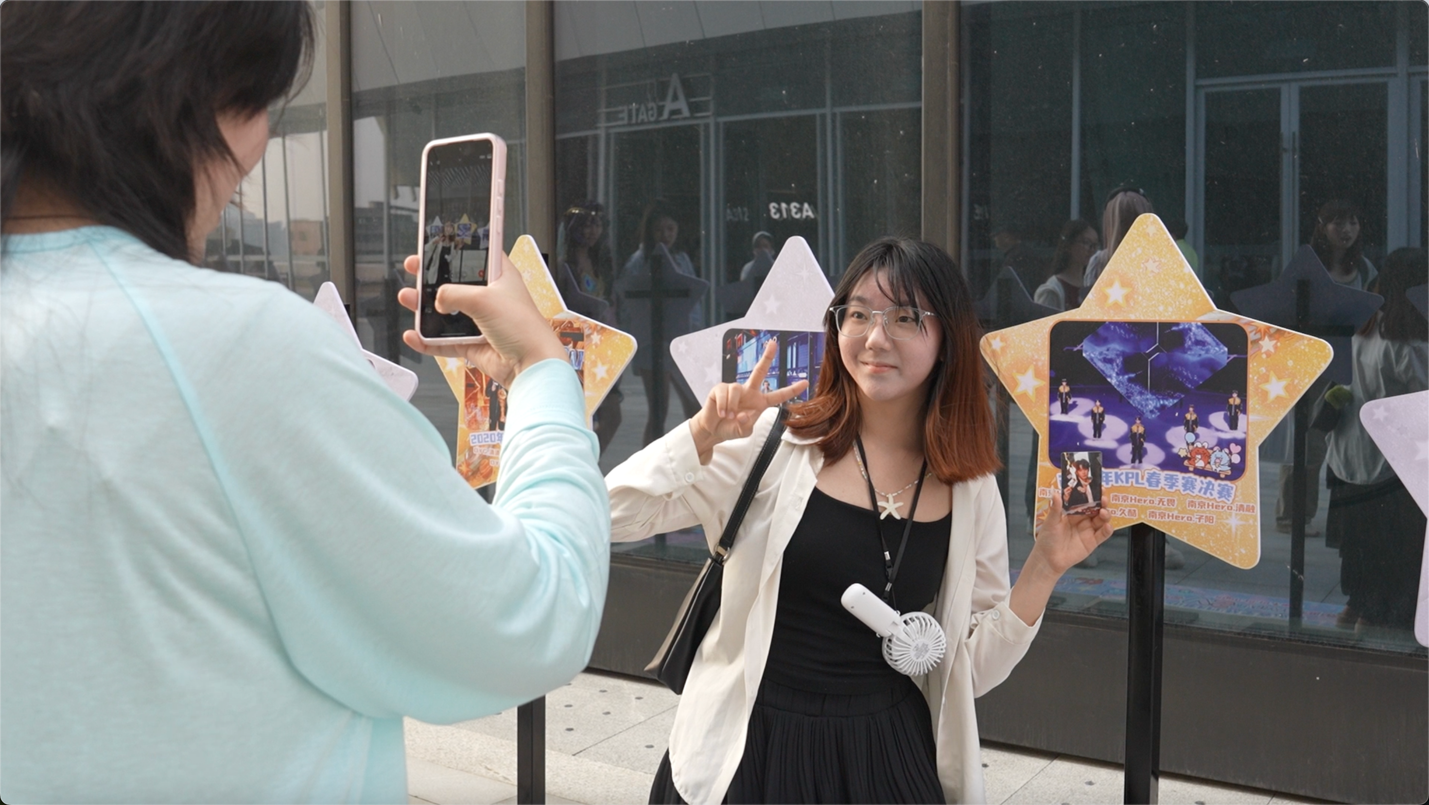 A spectator takes photos with the photo wall outside Wuyuan River Stadium in Haikou, south China's Hainan Province, April 11, 2026. /CGTN