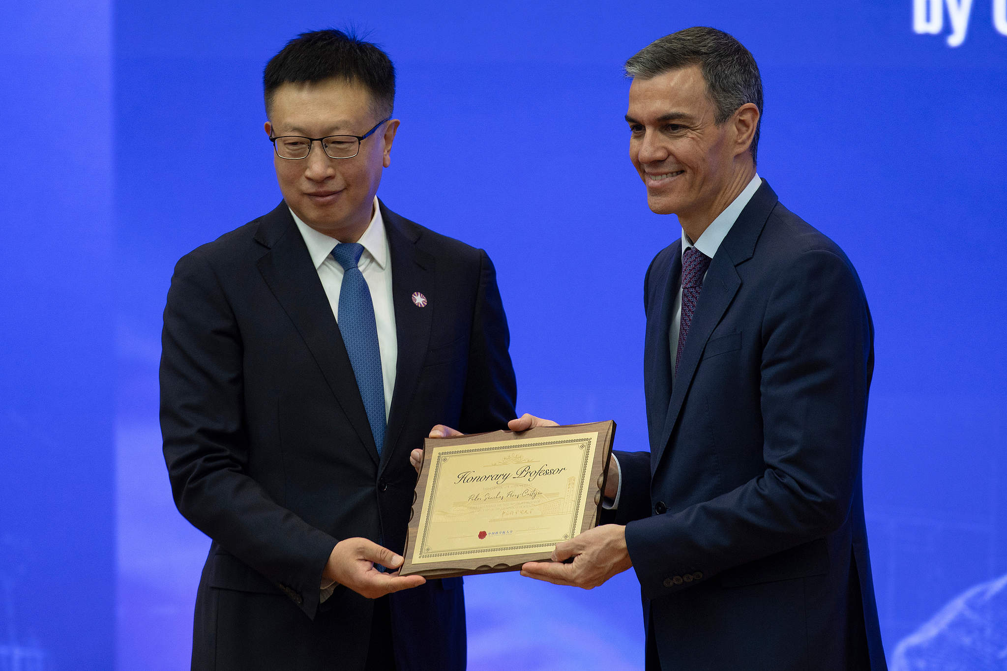 Spanish Prime Minister Pedro Sánchez (right) poses with a plaque after being named an honorary professor at the University of Chinese Academy of Sciences in Beijing on April 13, 2026. /VCG