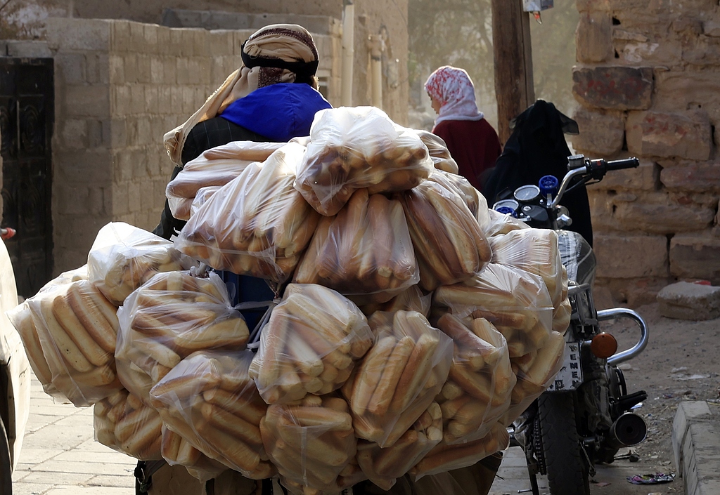  A man transports plastic bags filled with bread for sale on a motorcycle in Sana'a, Yemen, 22 December 2025. /CFP