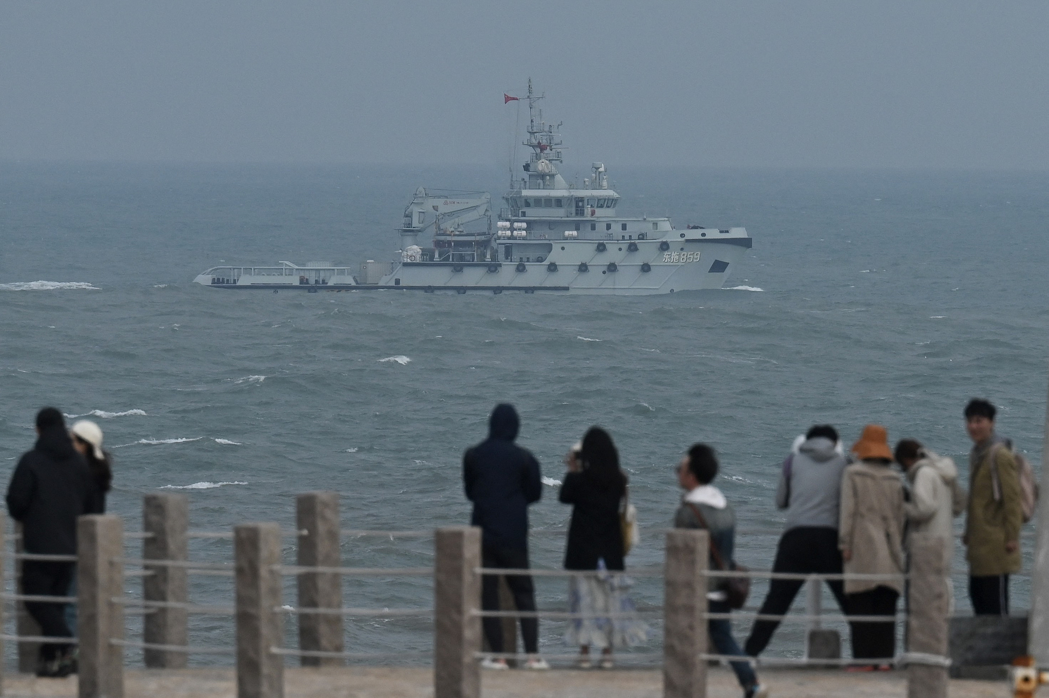 A Chinese Navy tugboat sails in the Taiwan Strait, past tourists on Pingtan Island, in southeast Fujian province, China, on April 7, 2023. /CFP