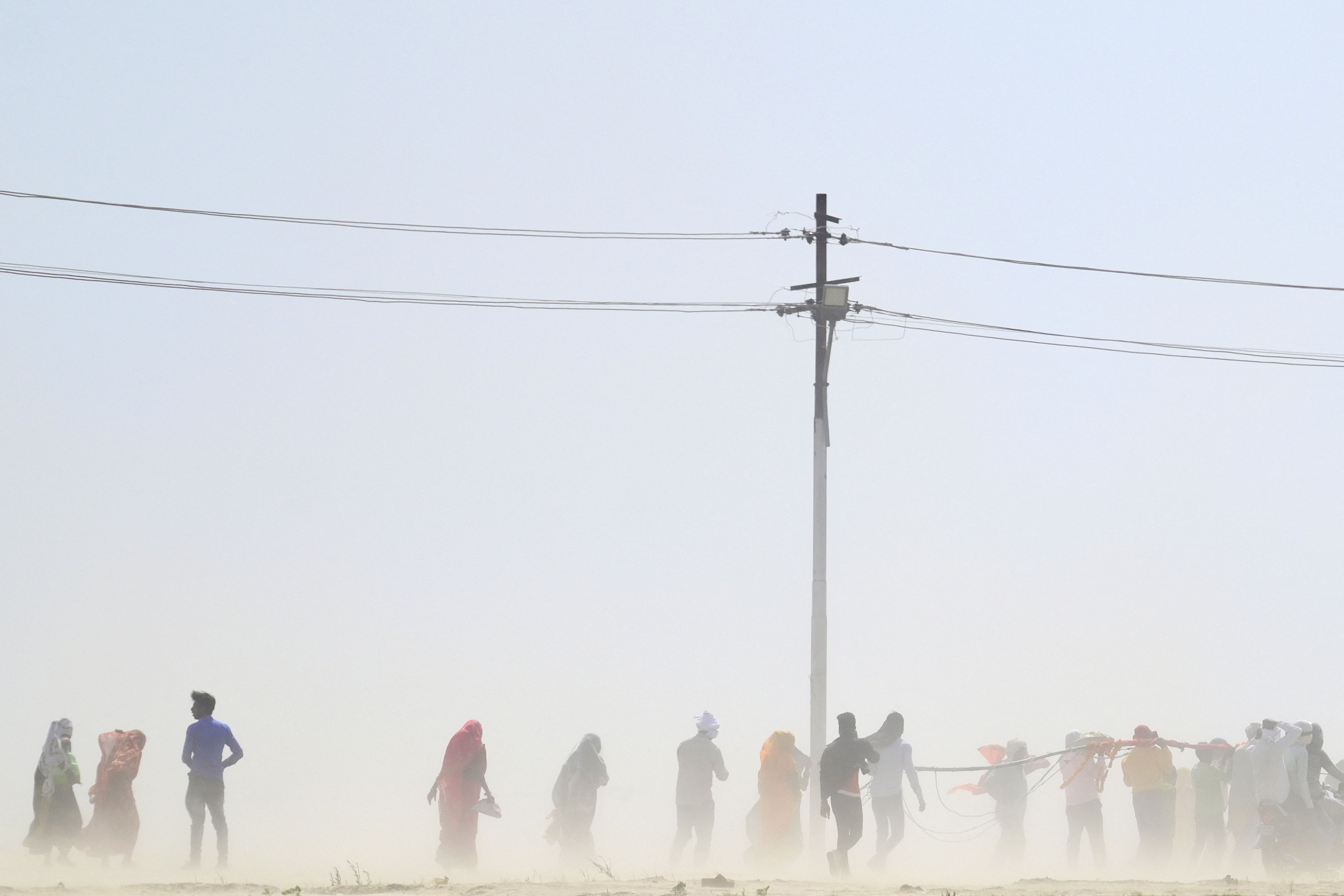 People walk through a dust storm on a hot summer day in Prayagraj, India, April 18, 2023. /VCG