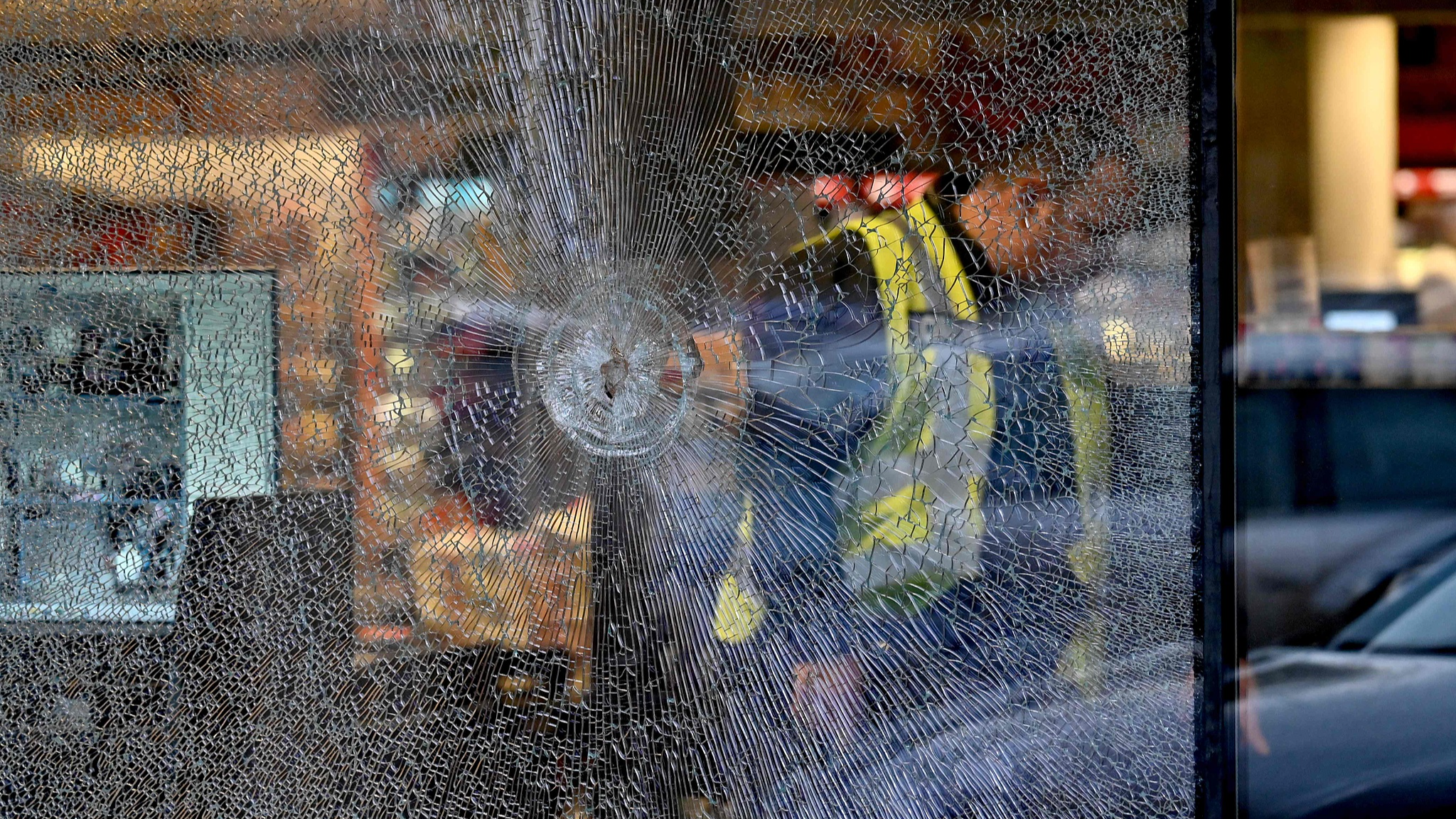 A policeman walks past a bullet hole in the window of a supermarket after a shooting in Kyiv on April 18, 2026. /VCG