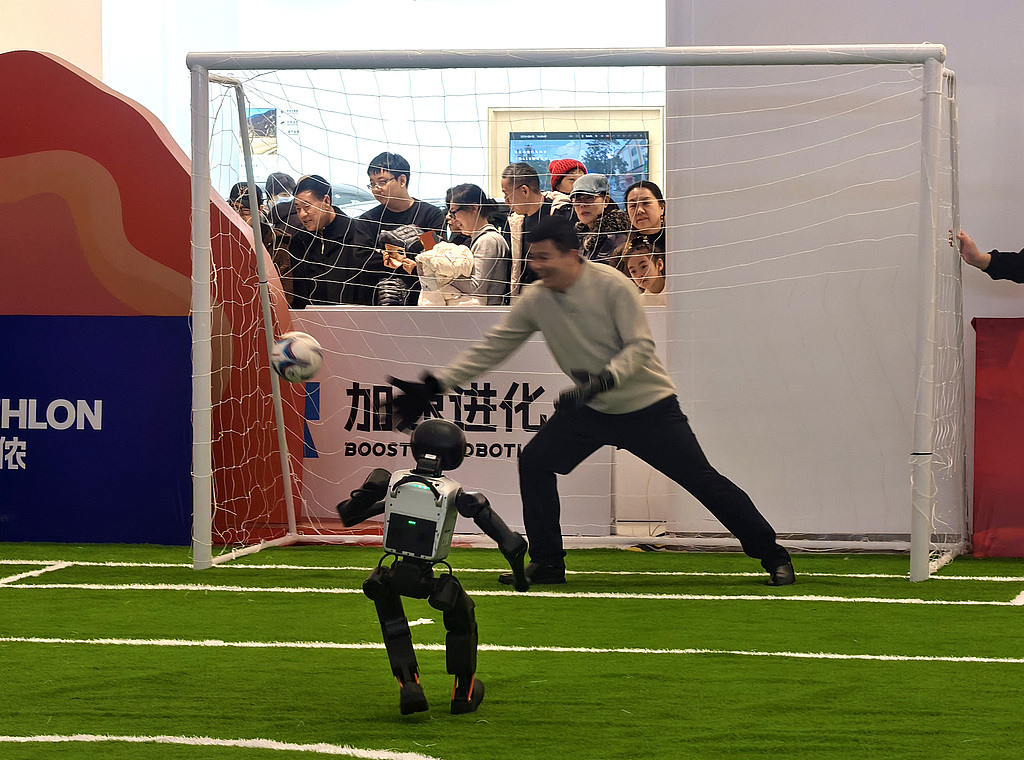 A robot shoots for goal against a human keeper at the Haidian New Year Technology Fair robot soccer field in Beijing on February 20, 2026. /VCG