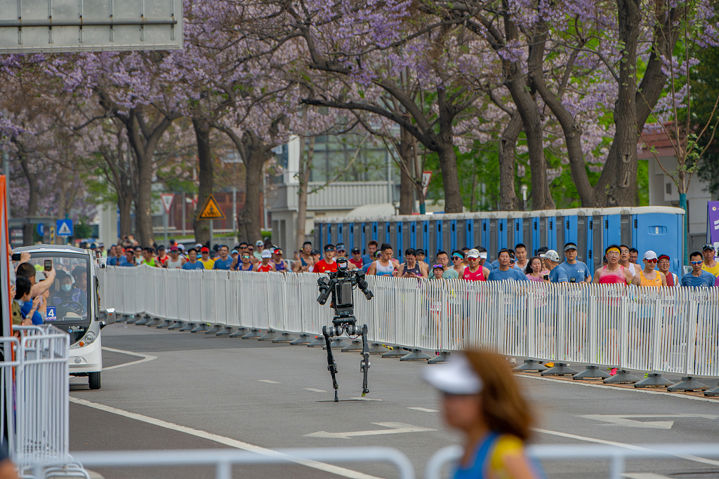 A robot sprints along the route of the Beijing Humanoid Robot Half-Marathon on April 19, 2026. Over 100 teams and more than 300 robots participated./VCG