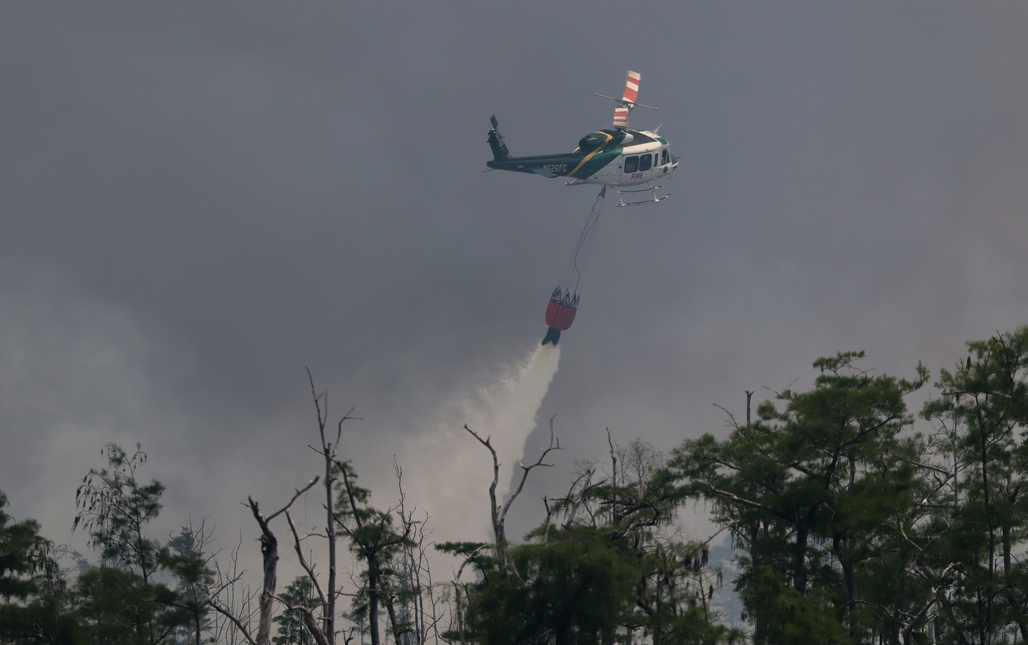 A helicopter dumps a bucket load of water on a wildfire in Naples, Florida, US, April 14, 2026. /VCG