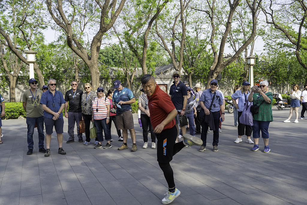 Foreign tourists experience old Beijing folk customs at the Bell and Drum Towers on the central axis of Beijing on April 22, 2026. /CFP