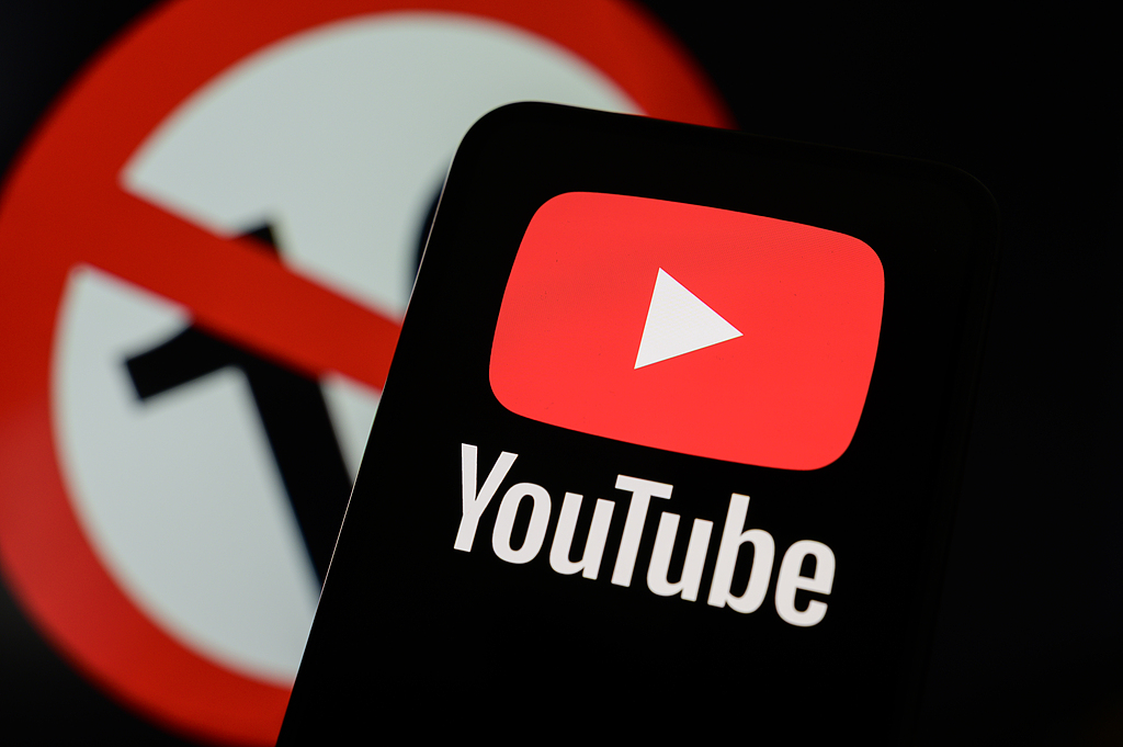 A smartphone displays the YouTube app against a backdrop of a 