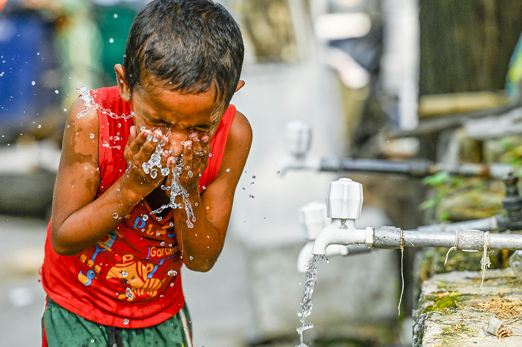A boy quenches his thirst from a water tank tap in Sanjay Camp Chanakyapuri, New Delhi, India, on June 12, 2025. /CFP
