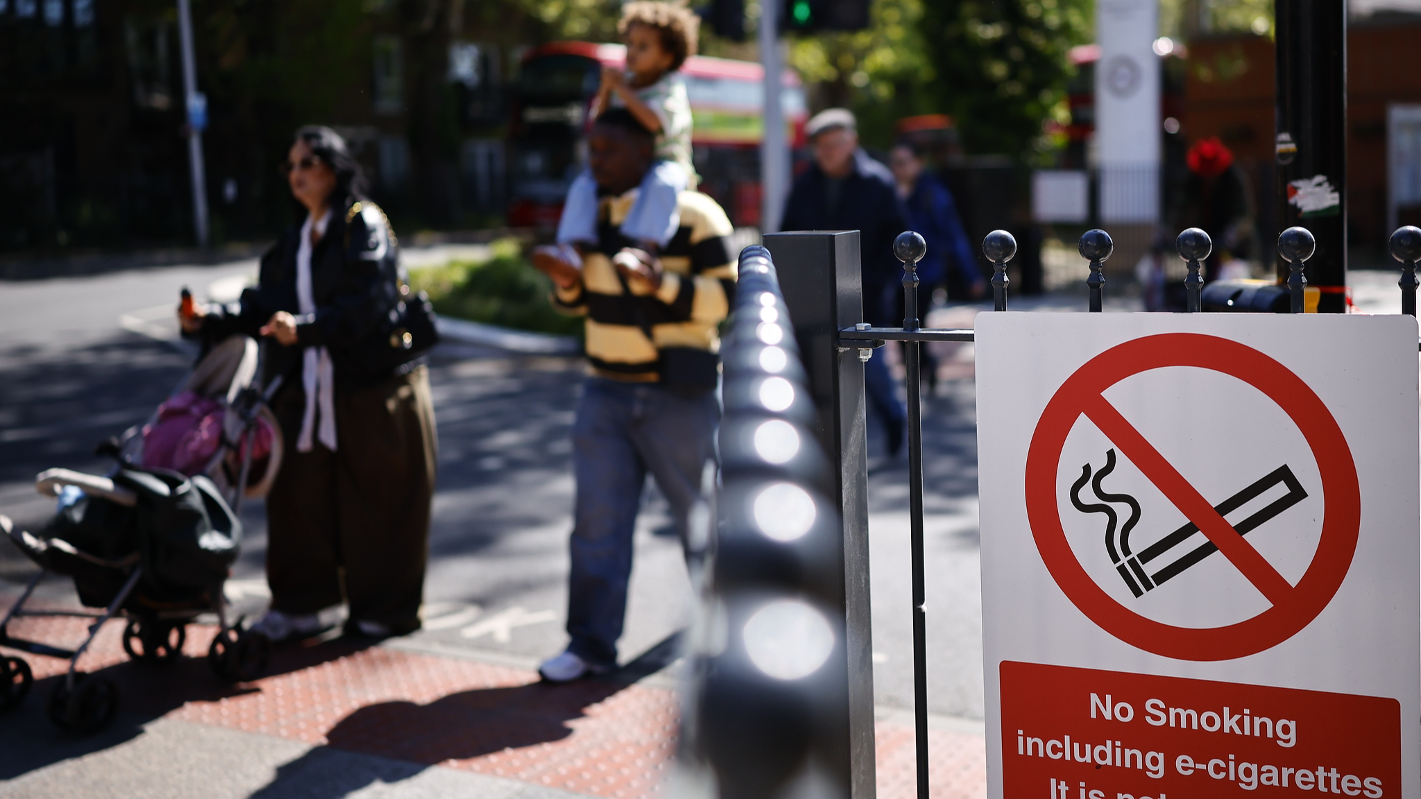 A family walk past a no smoking sign outside a bus station in east London, Britain, April 23, 2026. /VCG