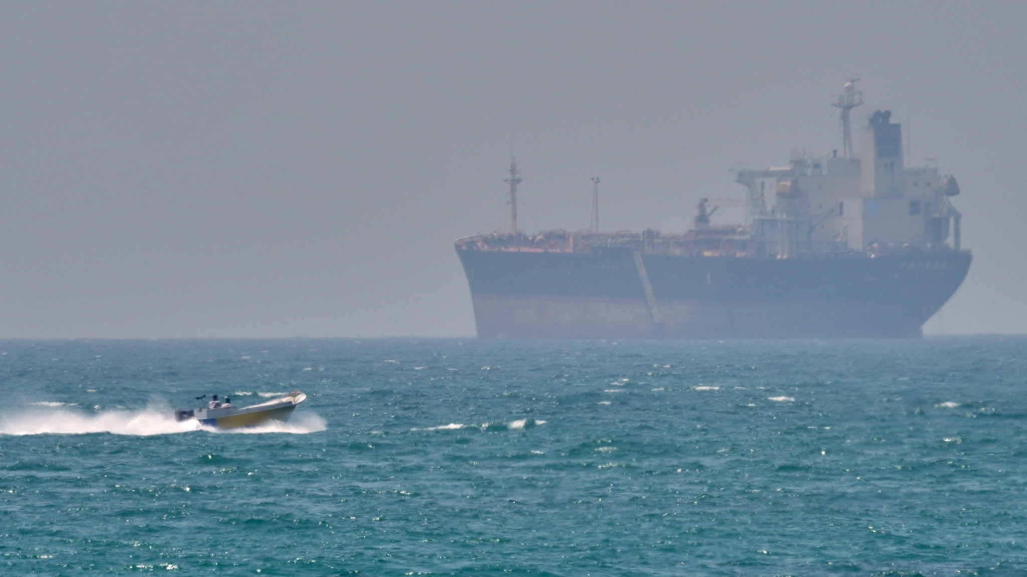 A boat sails past a tanker anchored in the Strait of Hormuz off the coast of Qeshm Island, Iran, April 18, 2026. /VCG