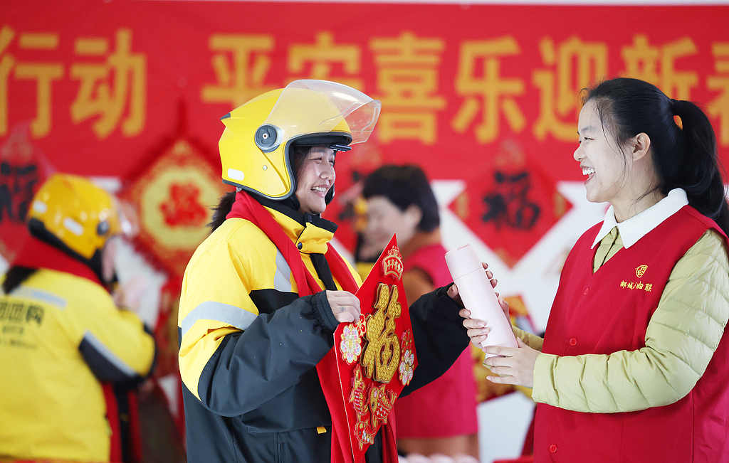 Volunteers from Women's Federation present scarves, festive Fu characters and water cups to female delivery riders, Linyi City of east China's Shandong Province, February 9, 2026. /VCG