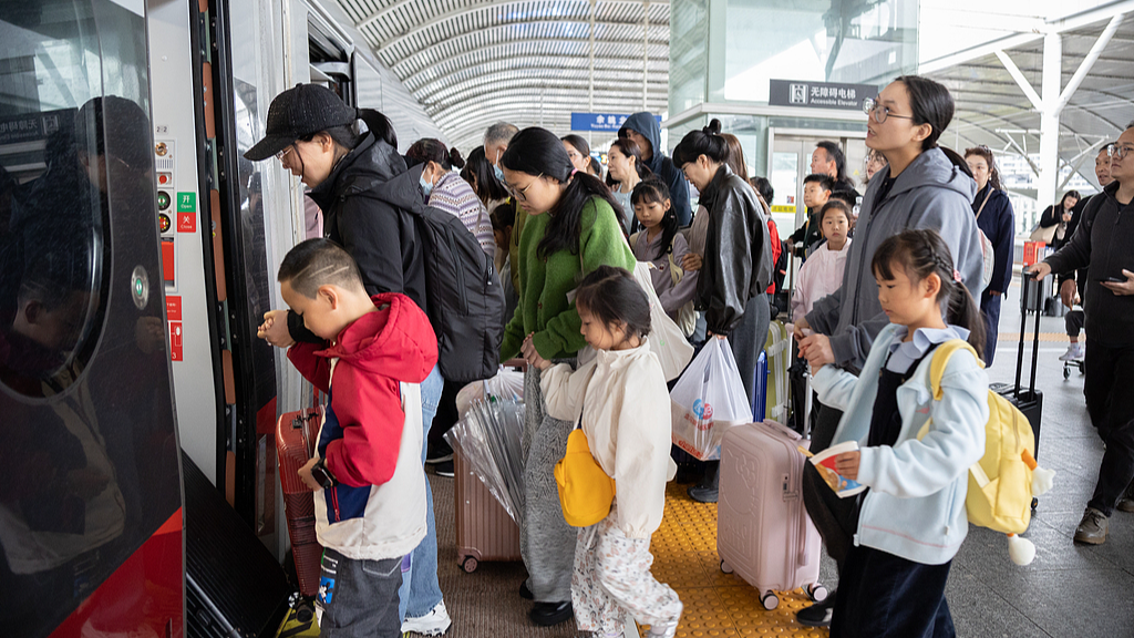 Parents and children line up to board a train at a railway station in Yuyao City, east China's Zhejiang Province, April 29, 2026. /VCG