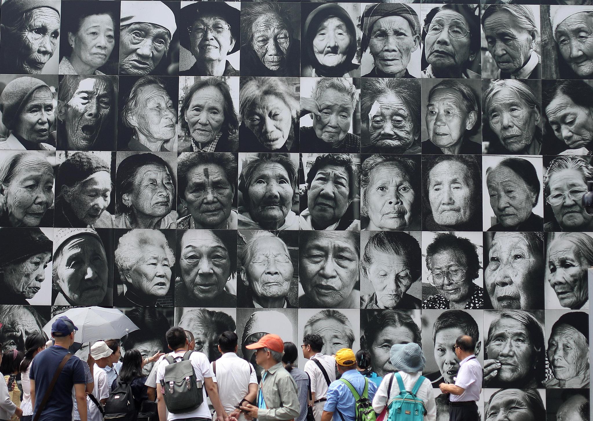 People visit the former site of the comfort station in Liji Lane, where a huge wall displays photos of 