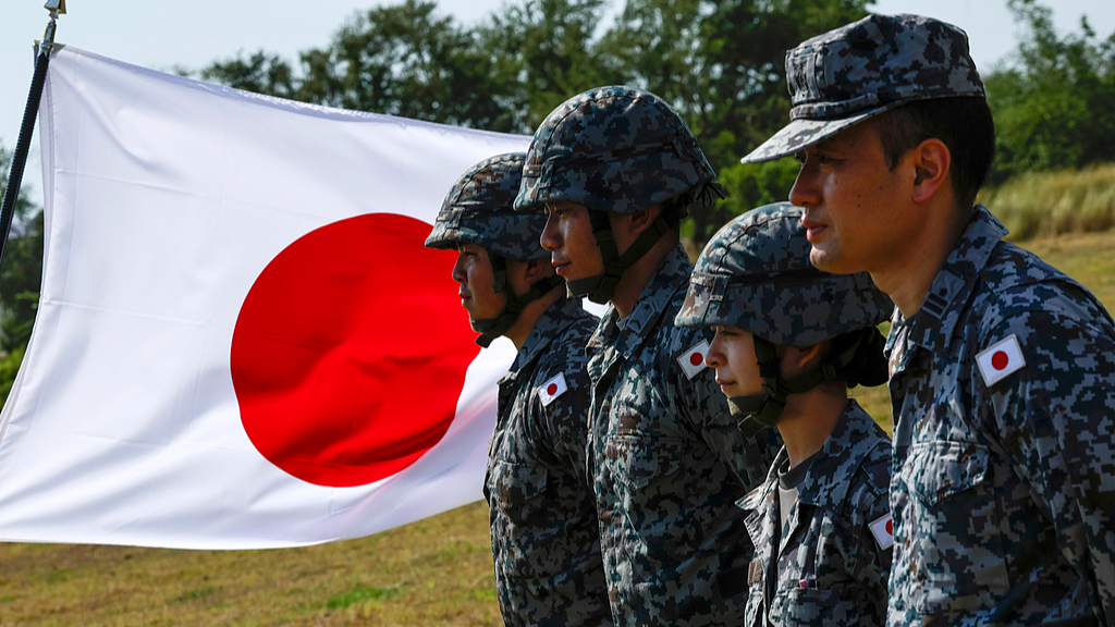 Officers of the Japan Air Self-Defense Force stand beside a national flag during the 