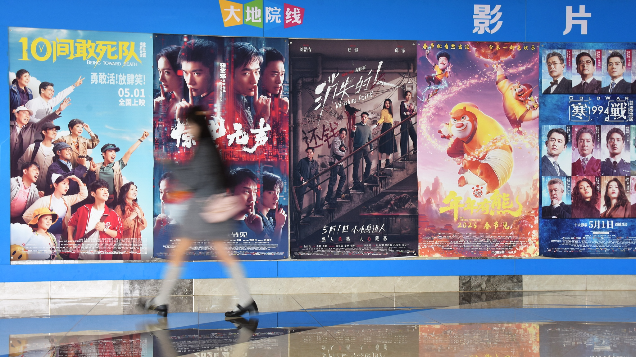 A young woman walks past film posters at a cinema in Mengzi City, Yunnan Province, China, May 3, 2026. /VCG