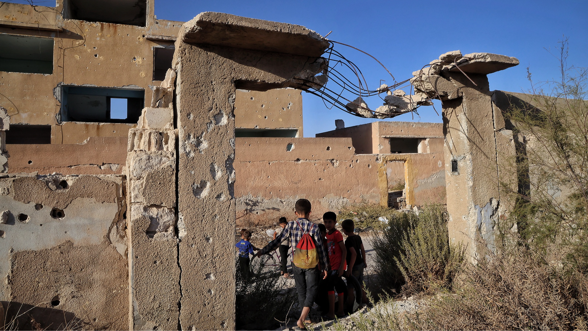 Children stand at the entrance of a school destroyed during the conflict between the former regime's forces and rebels in Hass, southern Idlib countryside, Syria, on September 21, 2025. /VCG