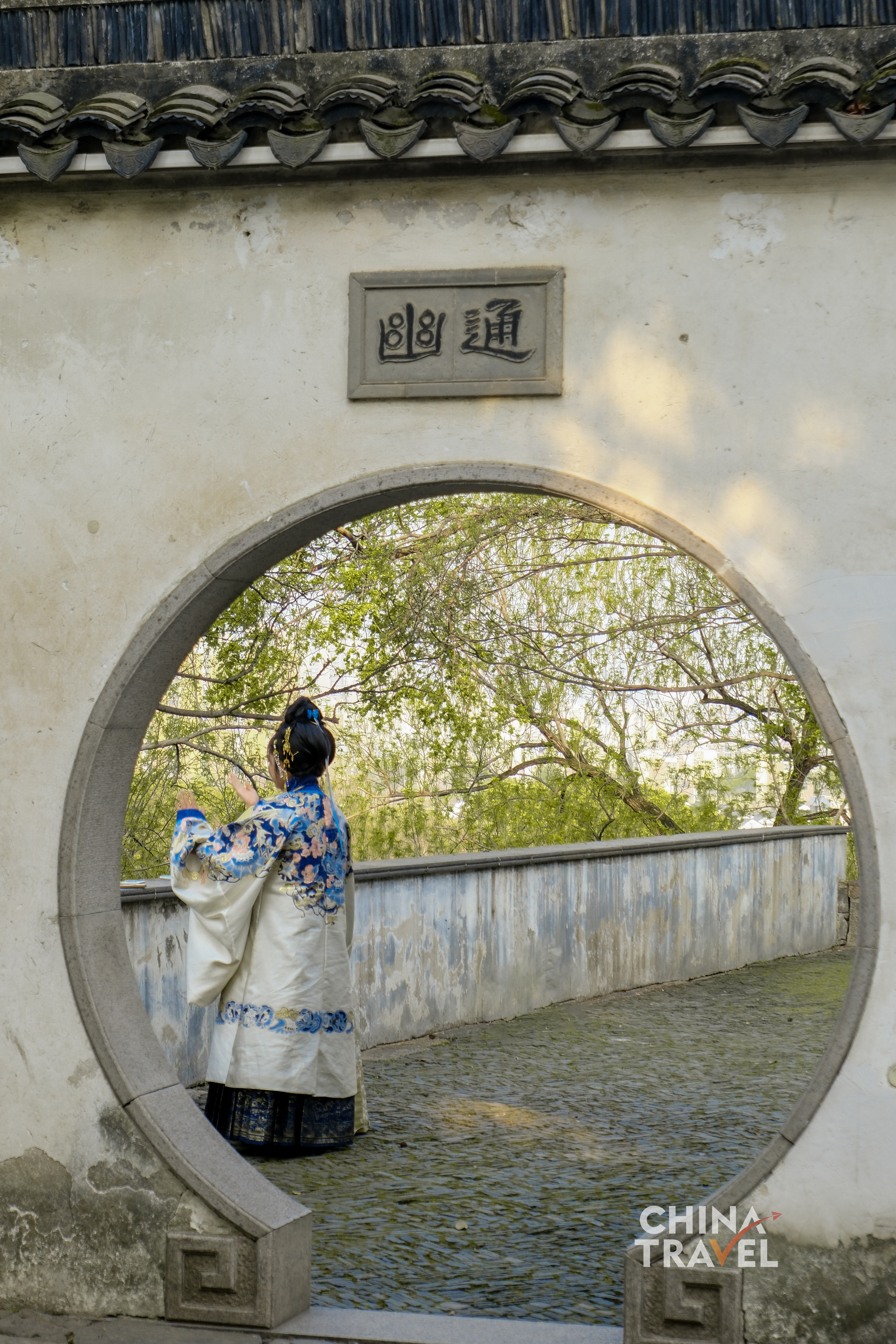 Visitors pause along the stone paths – some resting by the engraved cliff, others passing through the moon gates – becoming part of the garden’s unfolding rhythm. /CGTN