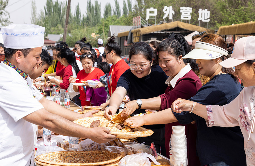 Visitors sample local delicacies such as the signature Naan, a baked flatbread, in Kuqa City, northwest China's Xinjiang Uygur Autonomous Region. May 1, 2026. /CFP