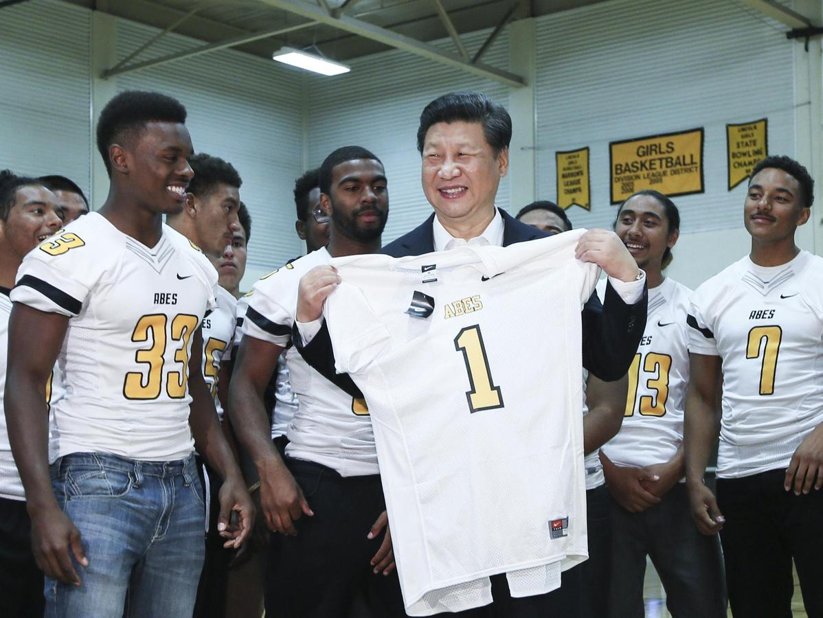 Chinese President Xi Jinping receives a football jersey presented by students from Lincoln High School, Tacoma City, Washington State, US, September 23, 2015. /Xinhua