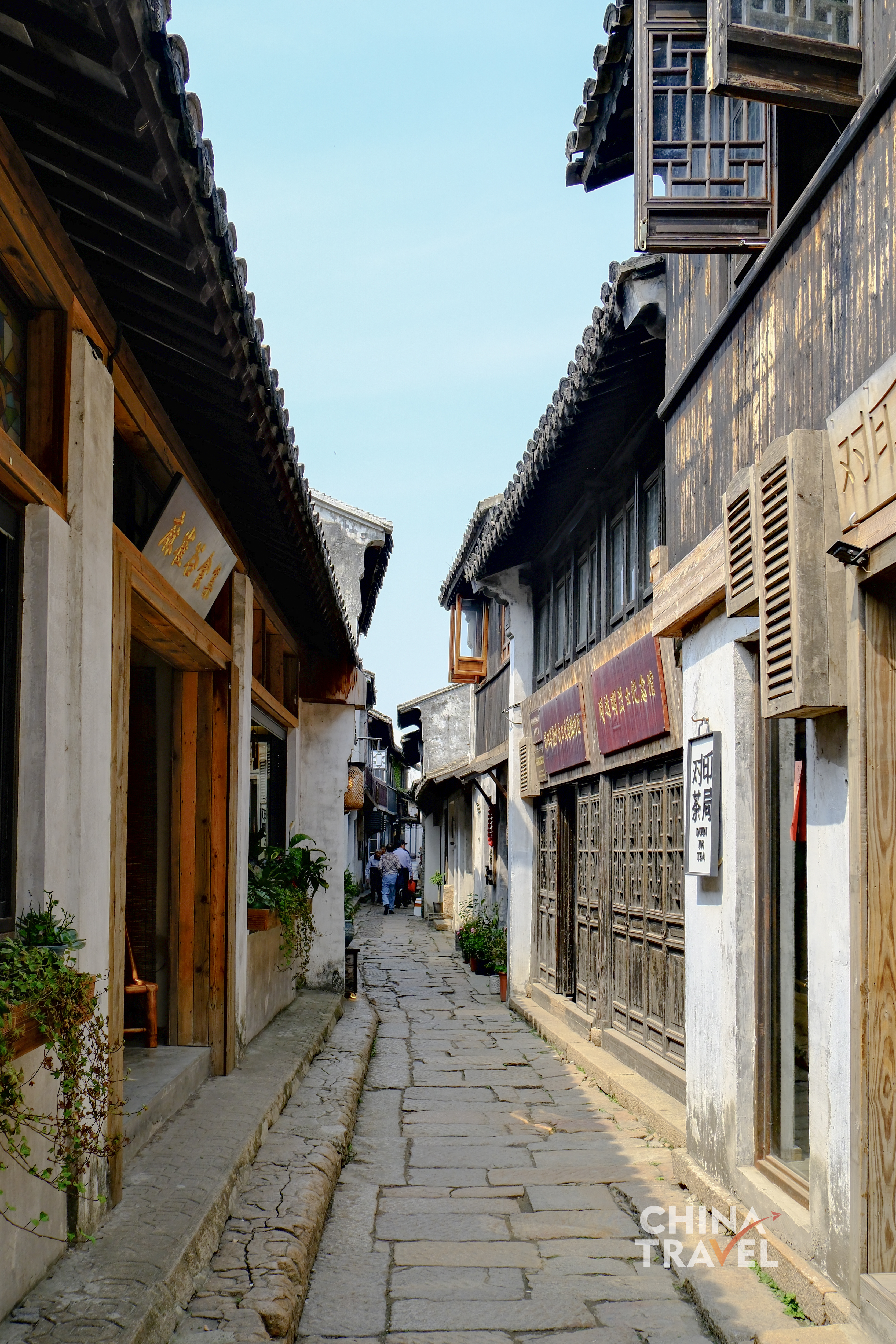 A narrow stone lane stretches between old wooden houses, where light falls unevenly across worn slabs and everyday life moves quietly through the passage. /CGTN