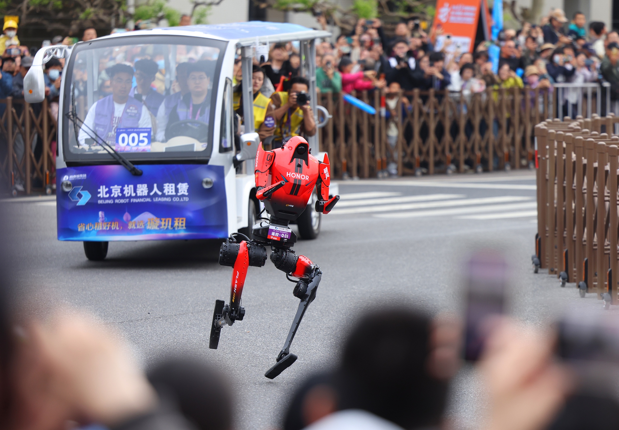 A humanoid robot accelerates through a turn during the half-marathon in Beijing E-Town, April 19, 2026. /VCG