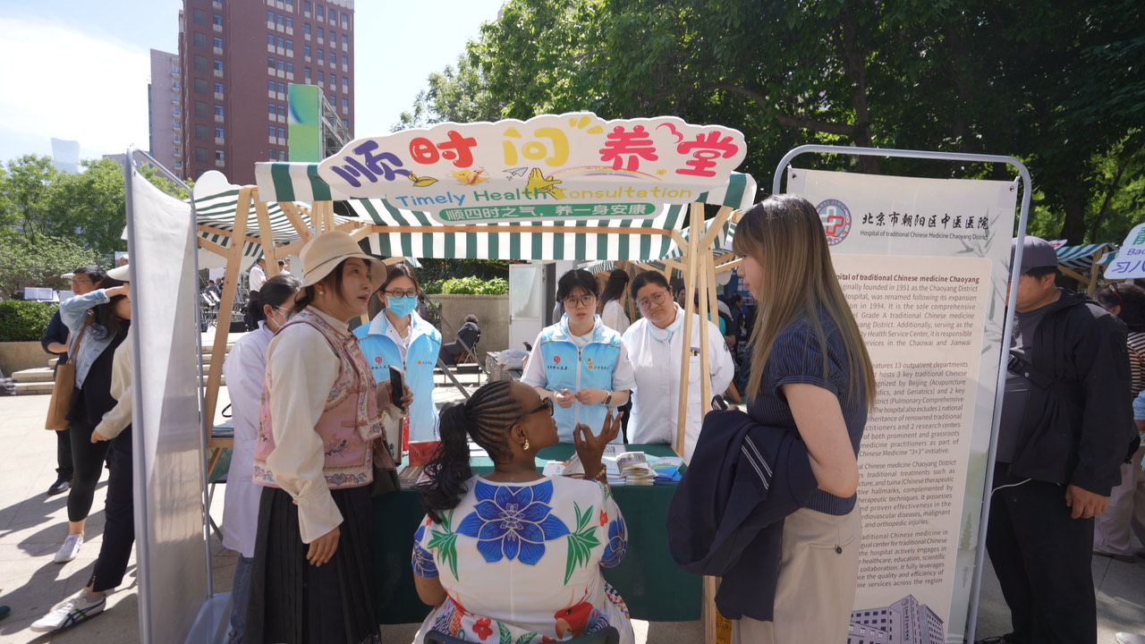 An international visitor consults TCM practitioners at a booth in the Jianwai Street neighborhood of Beijing on Sunday, May 10, 2026. /Photo provided to CGTN