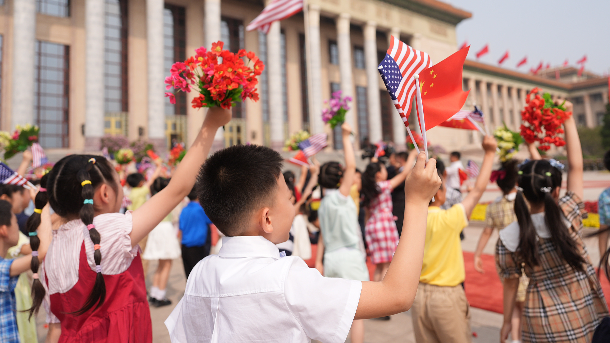 Children wave flowers and Chinese and American flags at the Great Hall of the People in Beijing, China, May 14, 2026. /VCG