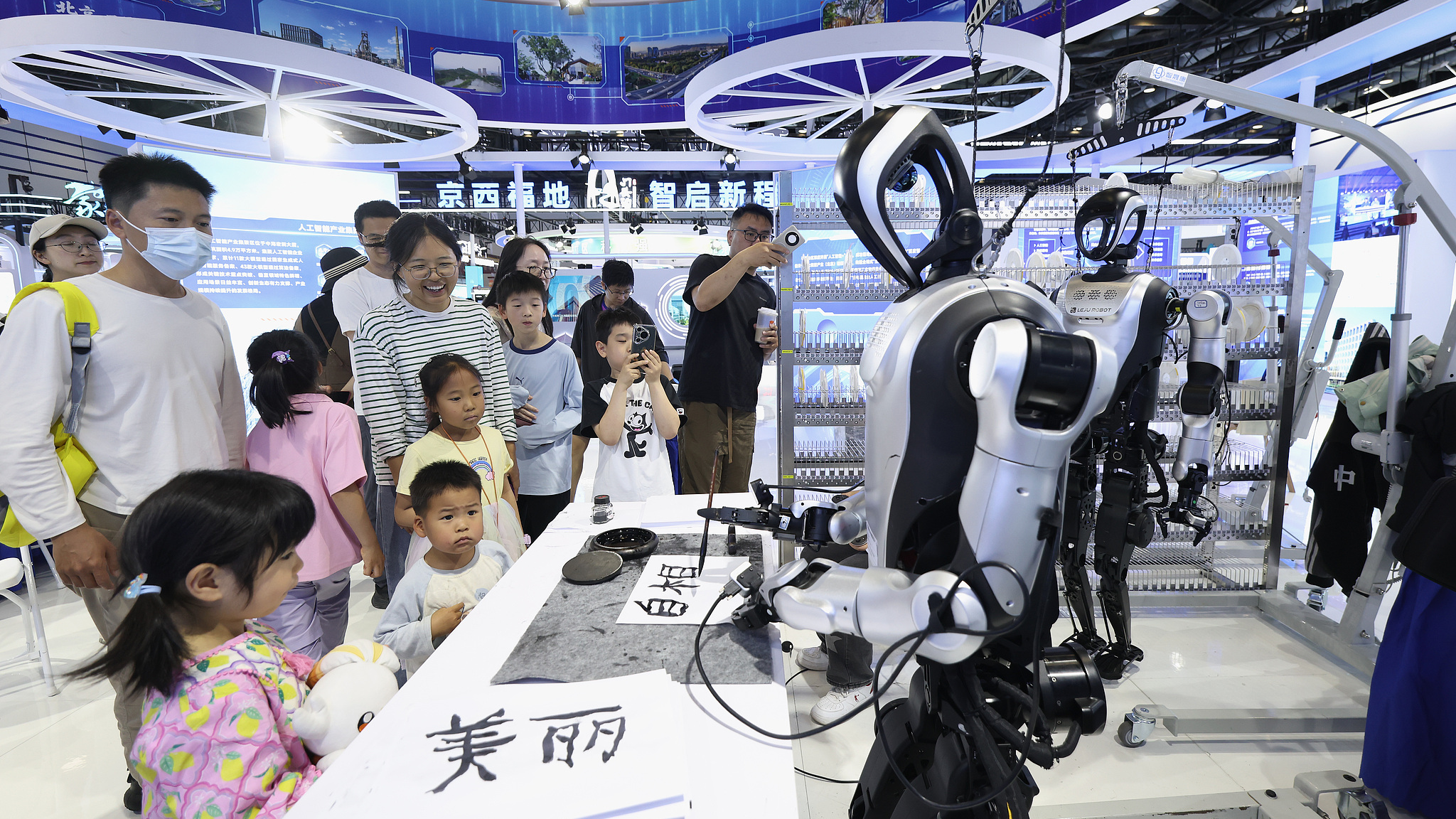 People watch a humanoid robot writing calligraphy at the 28th China Beijing International High-Tech Expo in Beijing, China, May 9, 2026. /VCG