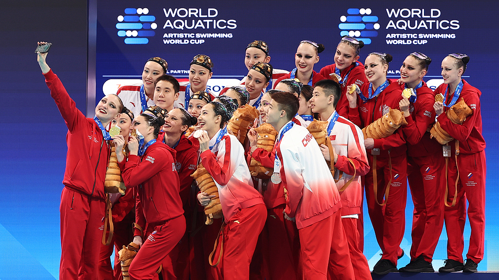 Team China and Russia take selfies together on the podium at the World Aquatics Artistic Swimming World Cup at the Xi’an Olympic Sports Center Natatorium on May 3, 2026. In the Team Technical final, Russia took the gold medal, while two Chinese teams claimed silver and bronze. /VCG