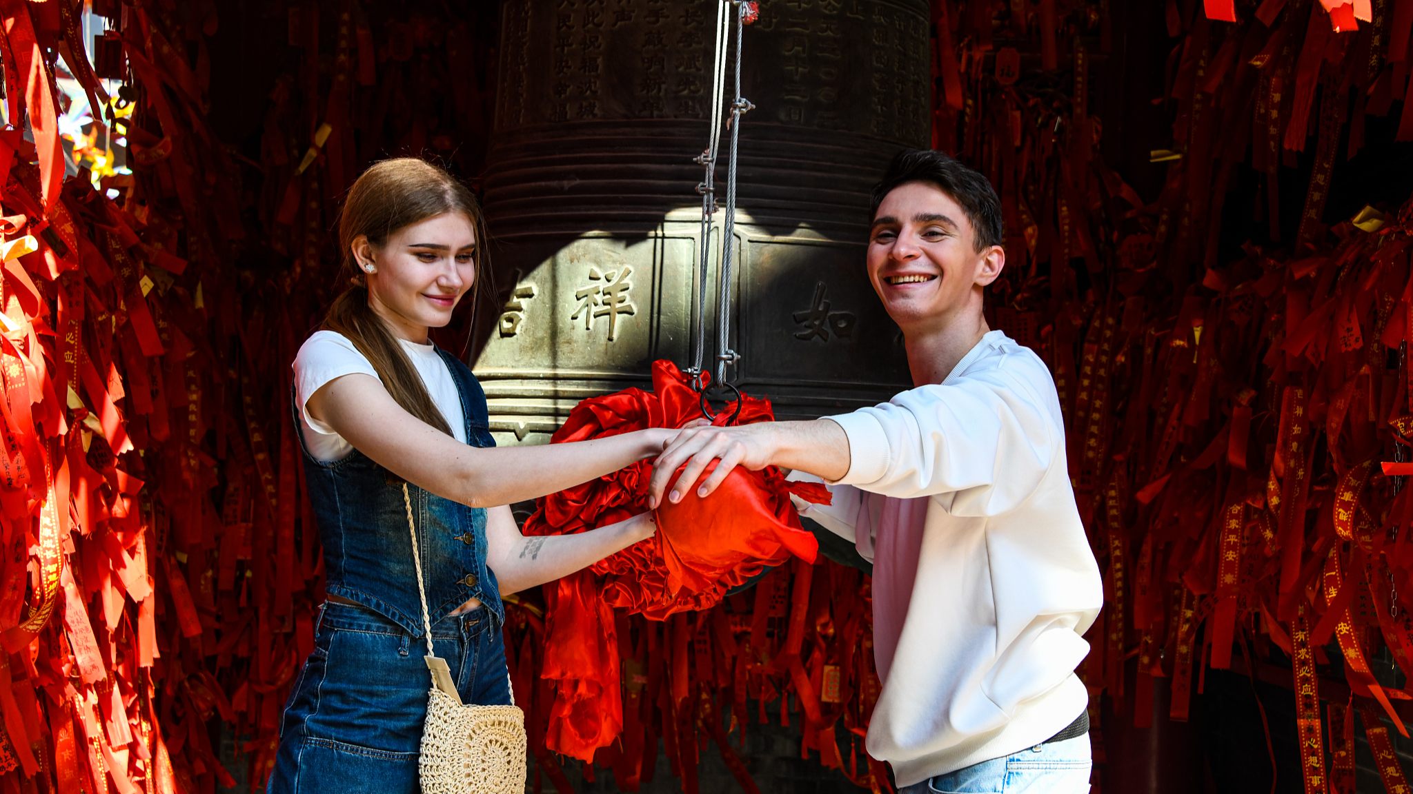 Two Russian students take part in a traditional blessing ritual at a scenic site in Shenyang, Liaoning Province, northeast China, May 11, 2025. /CFP