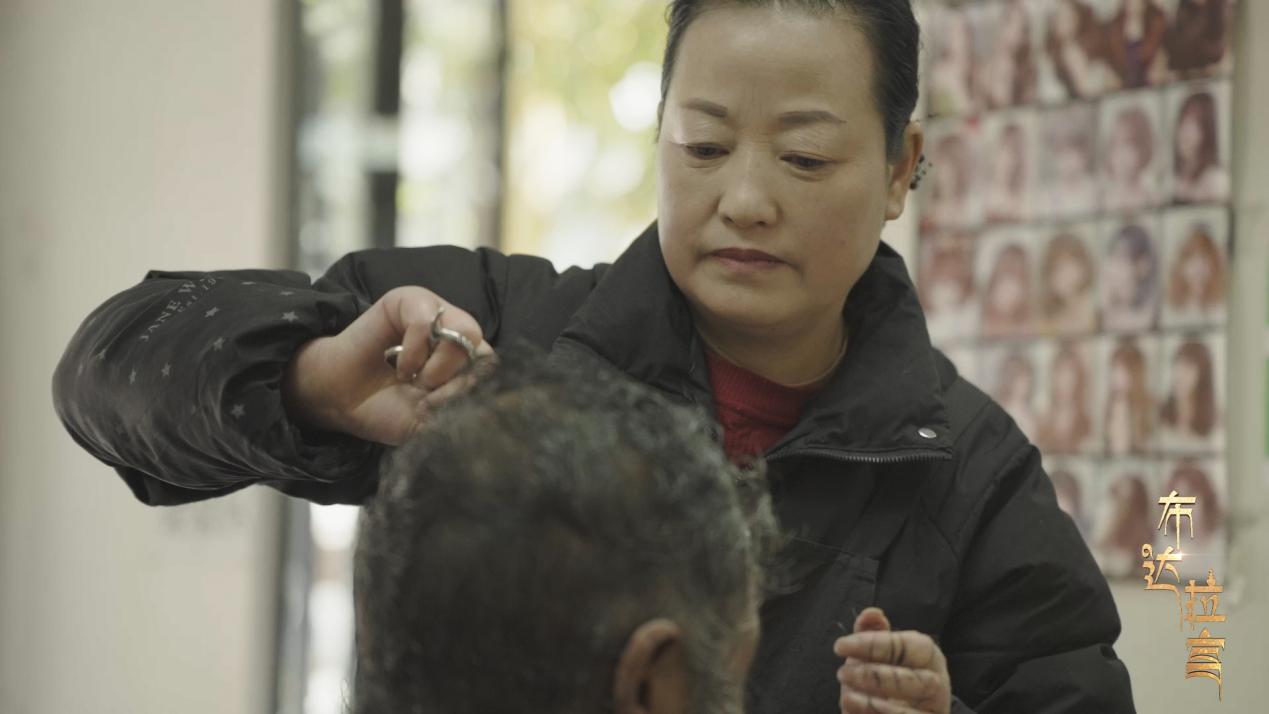 Yao Xiaoying, a barbershop owner, is giving a haircut to a community resident in Xigaze, China's Xizang. /CGTN