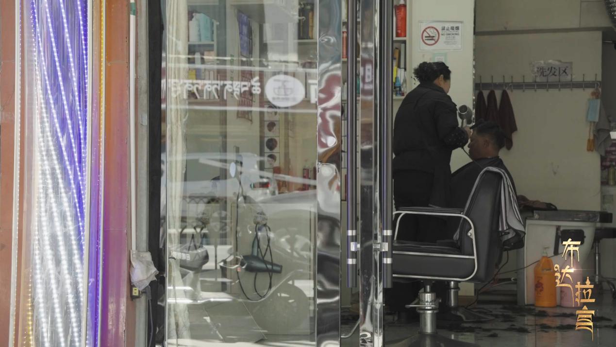 Yao Xiaoying, a barbershop owner, is giving a haircut to a community resident in Xigaze, China's Xizang. /CGTN